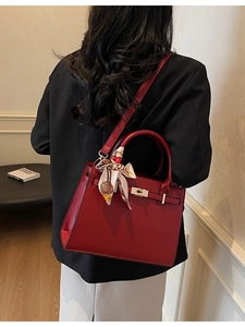 Elegant deep red leather handbag with gold clasp and silk scarf wrapped on handle