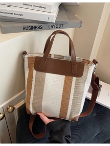 Vertical striped canvas tote bag with brown leather accents and adjustable shoulder strap