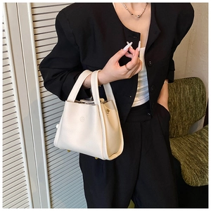 Detail of a creamy white litchi grain leather bucket bag with embossed logo and handles