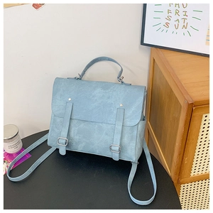 Detail of light blue vintage backpack with matte texture and dual buckle straps on a table