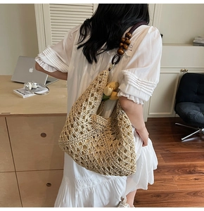 Detail view of woven straw tote bag featuring wood bead straps and geometric crochet patterns