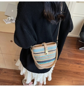 Detail of colorful striped straw bucket bag with leather strap on a female model