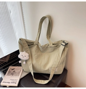 Gros plan du sac de voyage vert avec bandoulière réglable et porte-clés nuage en peluche