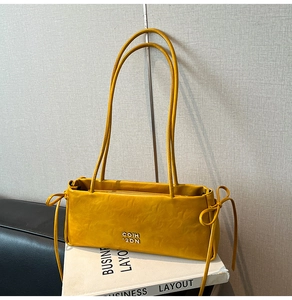 Détail du sac en cuir jaune avec nœuds décoratifs latéraux et logo en métal argenté