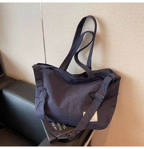 Détail du fourre-tout en nylon bleu marine montrant le tissu imperméable et l'étiquette