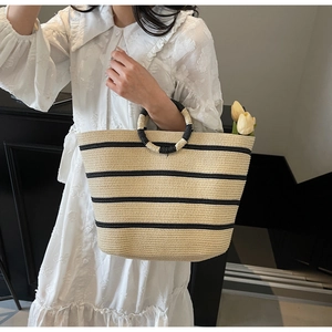 Detail of woven straw tote bag with black stripes and unique circular rope handles