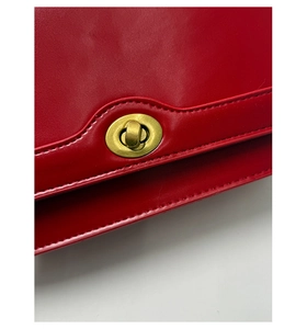 Macro detail of high-quality red leather bag with golden oval twist lock and fine stitching