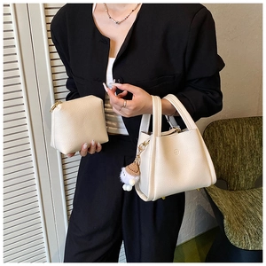 Detail of off-white lychee grain leather bucket bag with plush charm and inner pouch