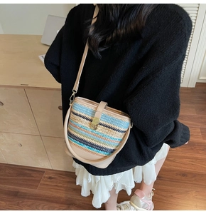 Detailed close-up of handmade woven straw bucket bag with multi-color stripes and leather trim