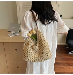 Detail of woven straw tote bag featuring wooden bead handles and floral decoration