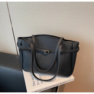 Close-up of black litchi pattern leather tote bag with elegant metal buckle detail