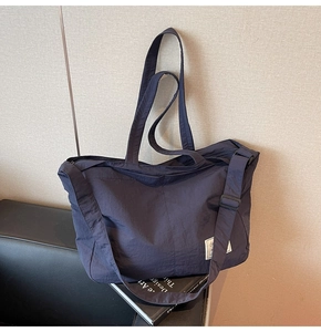 Vue détaillée du sac fourre-tout en nylon bleu marine avec bandoulière réglable et logo
