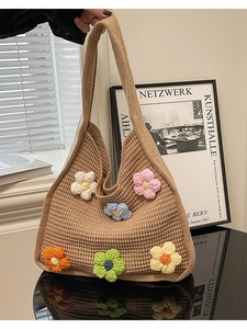 Khaki knitted tote bag with 3D crochet flowers and wide shoulder strap in artistic setting