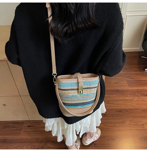 Detail of hand-woven bucket bag with multi-color stripes and beige leather shoulder strap