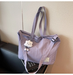 Détail d'un sac de voyage violet en nylon imperméable avec breloque nuage sur sofa