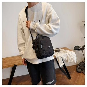 Detail of a black nylon crossbody bag with adjustable strap shown on a model