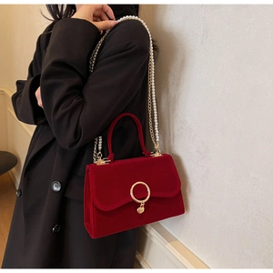 Detail of red velvet crossbody bag with pearl chain and golden ring hardware