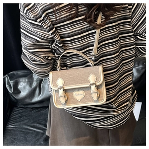 Detail of gray denim small square bag featuring heart-shaped leather patch and fashion buckle