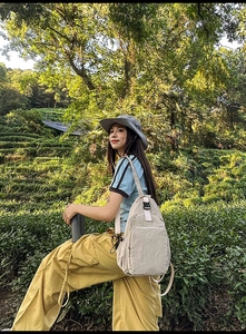 Outdoor lifestyle view of a beige nylon crossbody bag worn with a casual outfit
