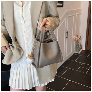 Detail view of grey pebble leather bucket bag with knitting charm and protective metal feet