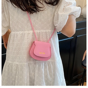 Pink mini crossbody bag for kids with yellow letter print on a lace dress model