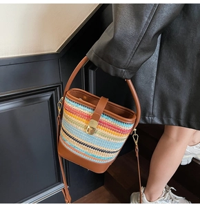 Detail of colorful woven straw bucket bag showing leather straps and gold metal clasp