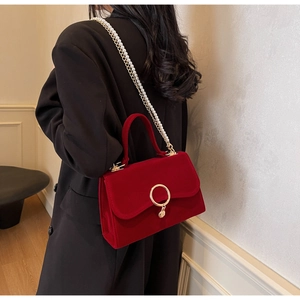 Detail of red velvet handbag with gold ring buckle and elegant pearl chain strap