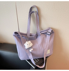 Détail d'un sac de voyage lavande avec breloque étoile sur un siège en cuir noir