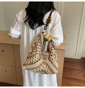 Close-up of beige woven tote bag featuring hollow patterns and dark wood bead handles