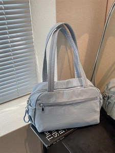 Light blue nylon tote bag with multiple pockets on a book in a minimalist setting