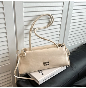 Gros plan du sac en cuir plissé crème avec logo métallique et détails de nœuds