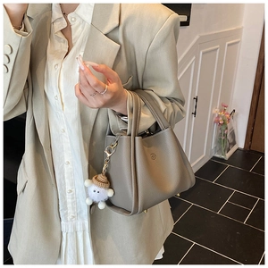 Close-up of grey litchi grain leather bucket bag with a plush lamb charm detail