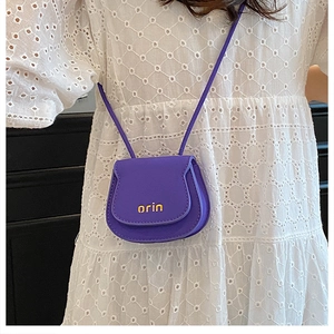 Detail shot of mini purple saddle bag with gold logo on white lace background