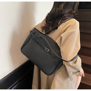 Detailed view of black lychee grain leather tote bag with thin straps and silver buckle
