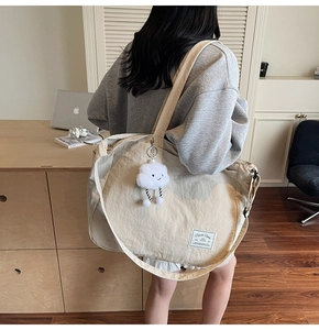 Détail du sac fourre-tout en toile beige avec bandoulière et breloque nuage douce
