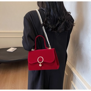 Elegant red velvet bag with gold heart clasp and pearl chain strap on shoulder