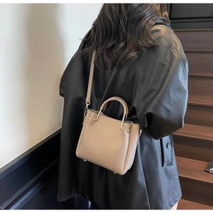 Detail of light brown lychee grain leather crossbody bucket bag with metal handle