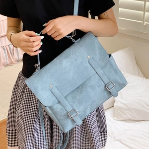 Light blue vintage messenger backpack in suede texture shown in a minimalist home setting