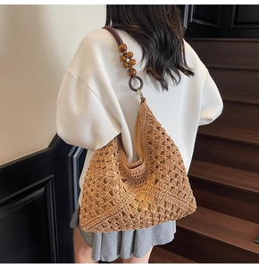 Detail of hand-woven straw tote bag with brown fabric lining and dark wood bead shoulder strap