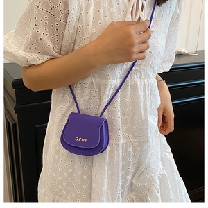 Detail view of mini purple leather saddle bag with gold logo and matching shoulder strap