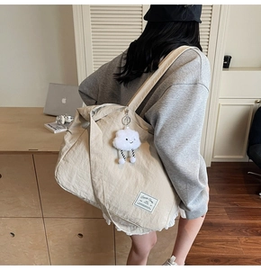 Détail du sac cabas en toile beige avec pendentif nuage blanc et étiquette en tissu chic