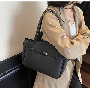 Detail of black pebbled leather tote bag with gold buckle and stylish shoulder strap