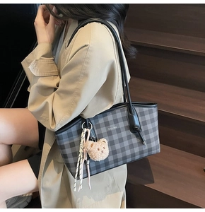 Close-up of checkerboard tote bag with plush bear charm and woven rope tassel detail