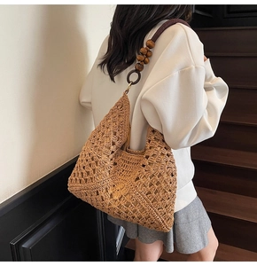 Detail of hand-woven straw tote with dark brown cord strap and decorative wooden beads