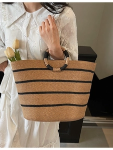 Handmade woven straw tote bag with black stripes and circular handles for beach vacations