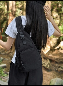 Outdoor view of multi-functional black nylon crossbody bag on a model in the forest