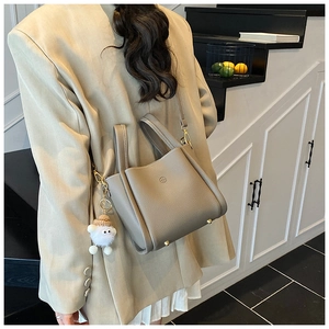 Detail of khaki bucket bag with lychee grain texture and cute plush toy charm