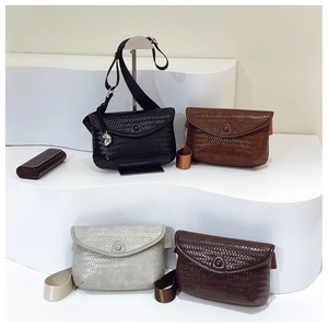 Détail de quatre sacs bandoulière tissés en noir, gris et marron sur supports blancs