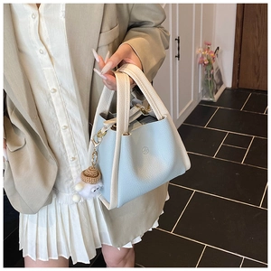 Close-up of light blue pebbled leather bucket bag with cream trim and character charm