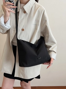Minimalist black half-moon shoulder bag with wide strap and silver metal logo detail